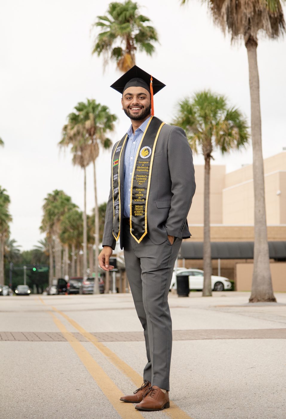Mehul Patel in cap and stole at his UCF graduation, the stole bearing Zimbabwe's flag