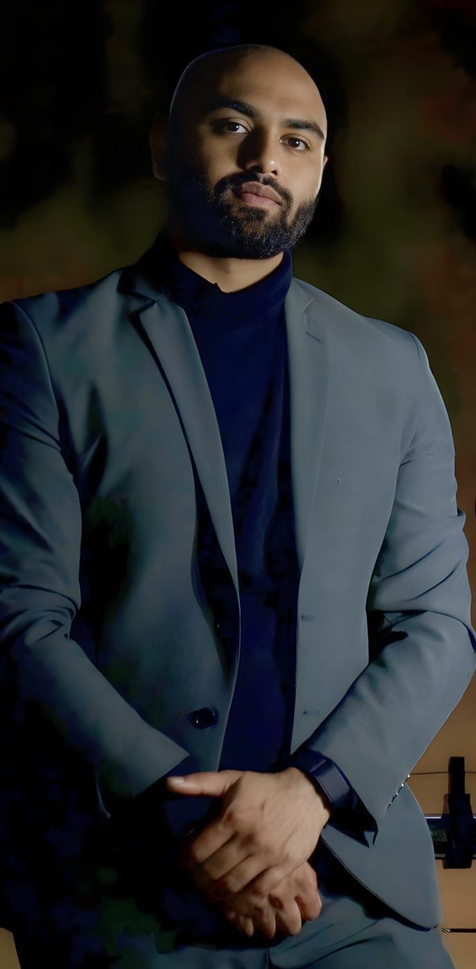 Portrait of Mehul Patel in a grey suit against a dark background